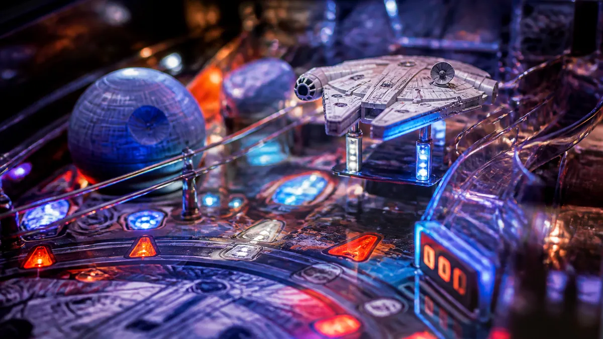 Gros plan sur le plateau d'un flipper de science-fiction avec ses rampes et ses cibles éclairées