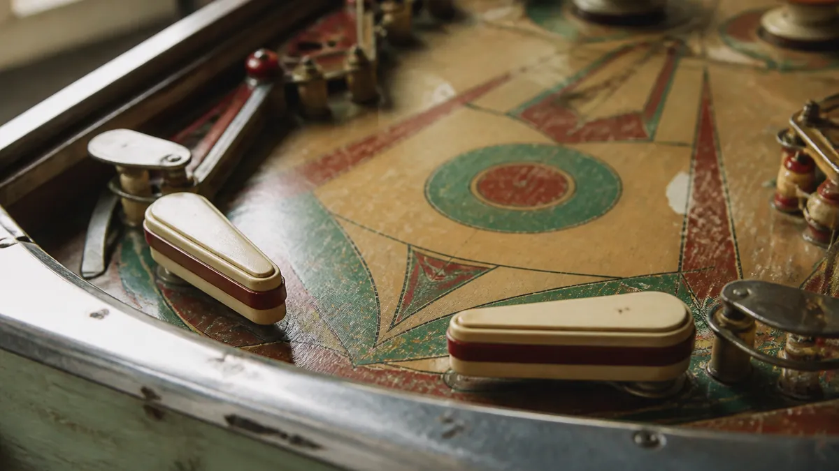 Gros plan sur les batteurs et le plateau d'un flipper électromécanique des années 1950