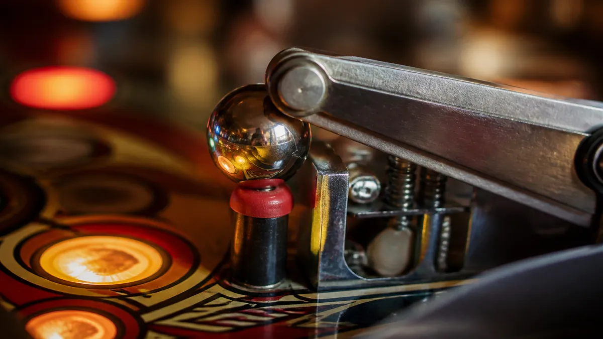 Gros plan sur un batteur de flipper tenant une bille en position de cradle